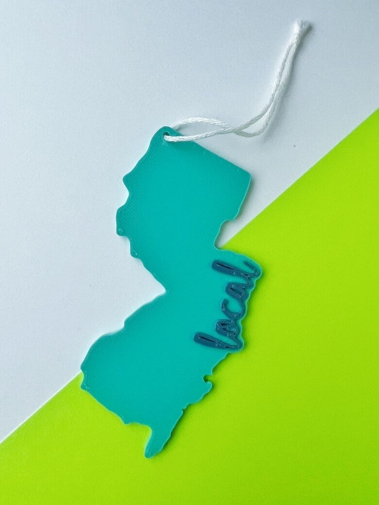 Teal 3D printed New Jersey local ornament with white string on a gray and lime green background