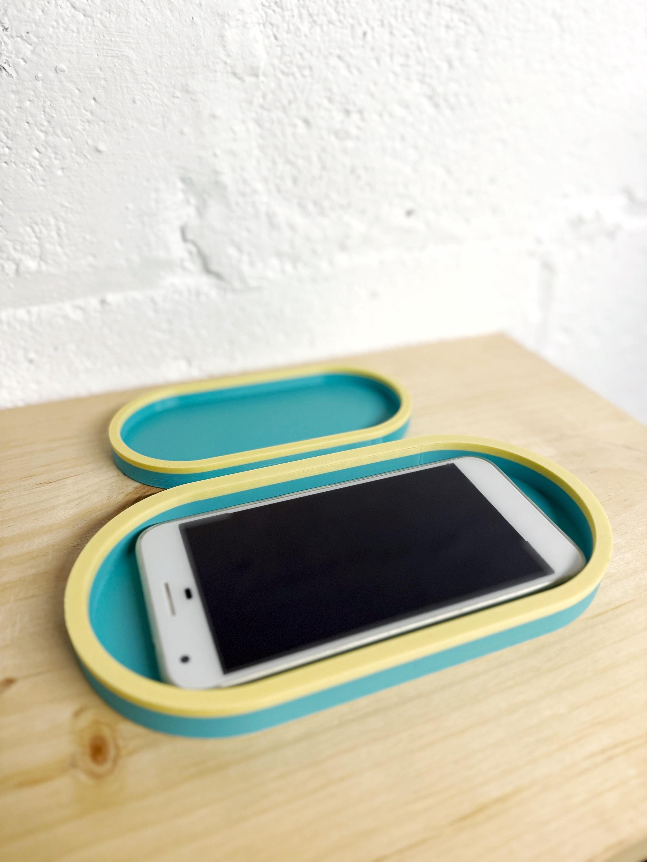Large and small two-tone catch-all trays on a wood shelf, the large one holding a phone