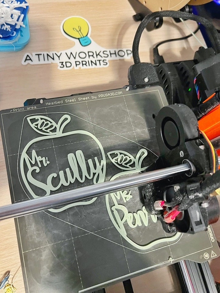 Personalized apple ornaments reading Mr Scully being 3D printed on the printer bed