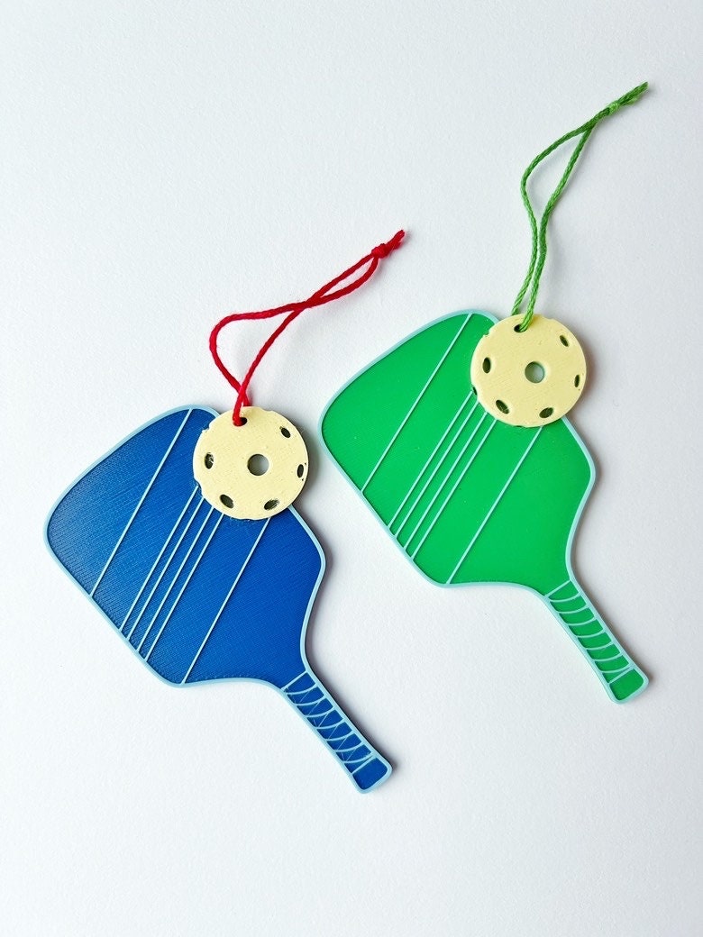Blue and green pickleball paddle ornaments with yellow balls and hanging string