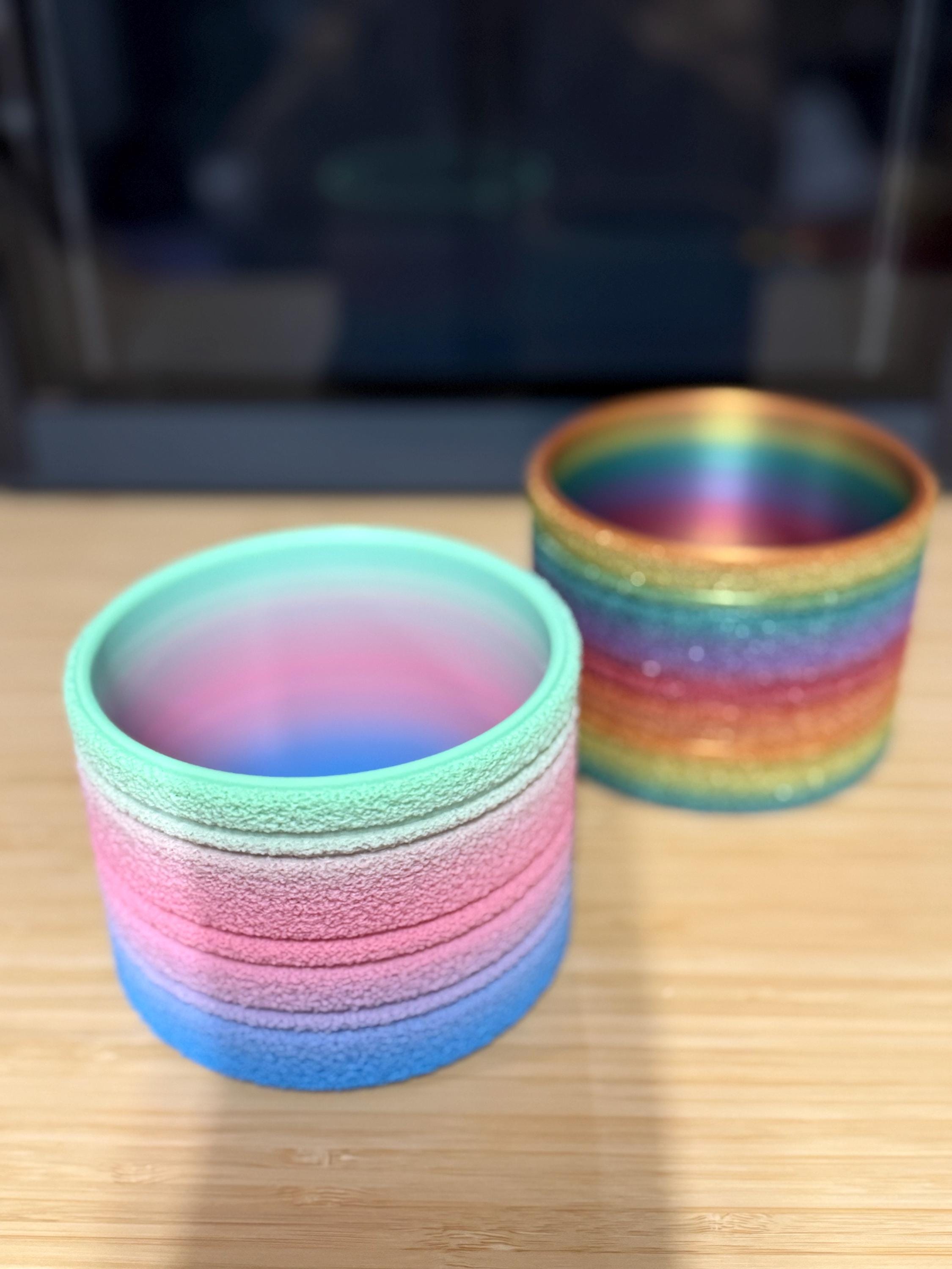 Pastel rainbow and classic rainbow fuzzy planters side by side, empty, showing both color options