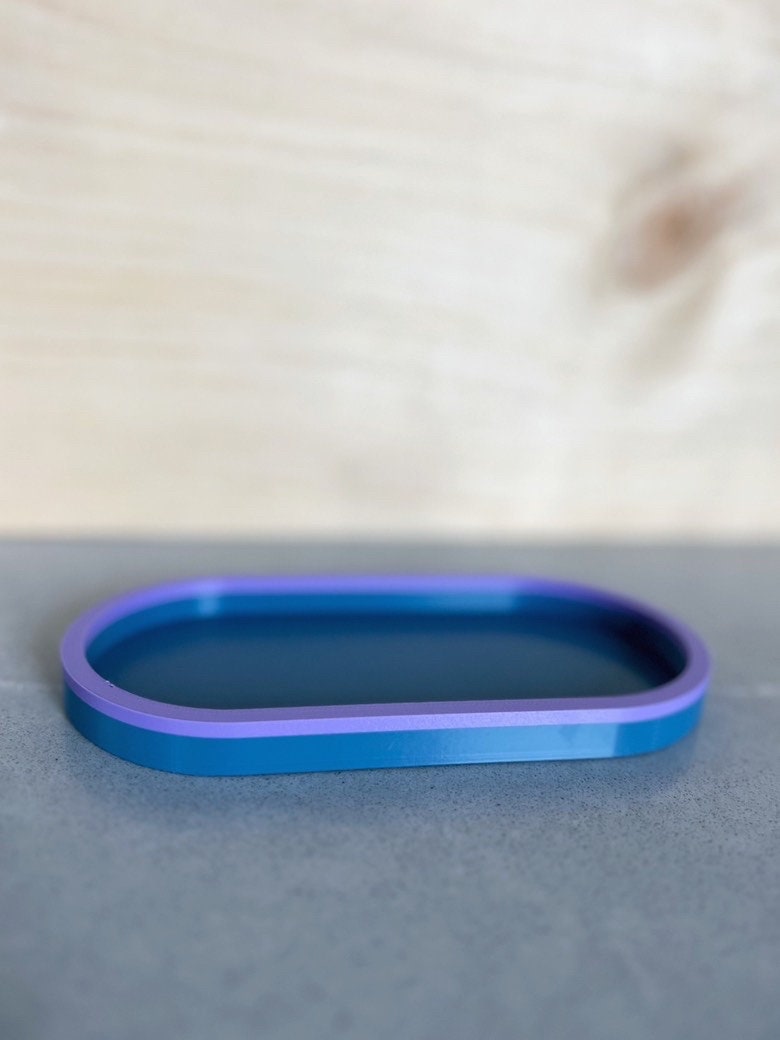 Blue on blue two-tone oval tray, side view, on a gray surface