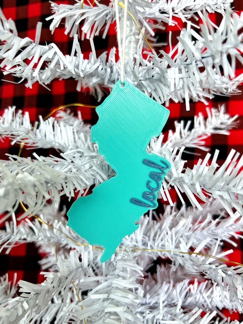 Teal New Jersey local ornament hanging on a white Christmas tree with buffalo plaid