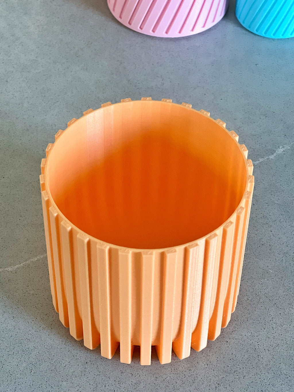 Empty peach 3D printed Modern Fluted Planter seen from above, showing the drainage slots in the base