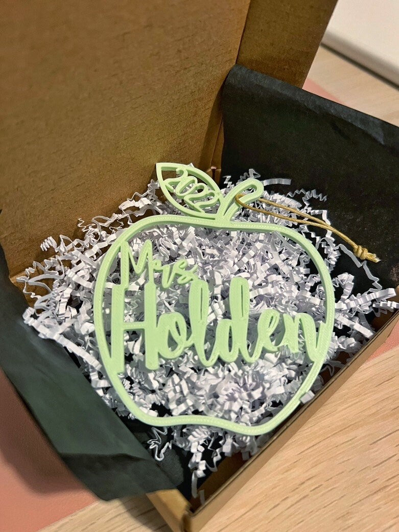 Personalized teacher apple ornament packed in a gift box with white crinkle paper