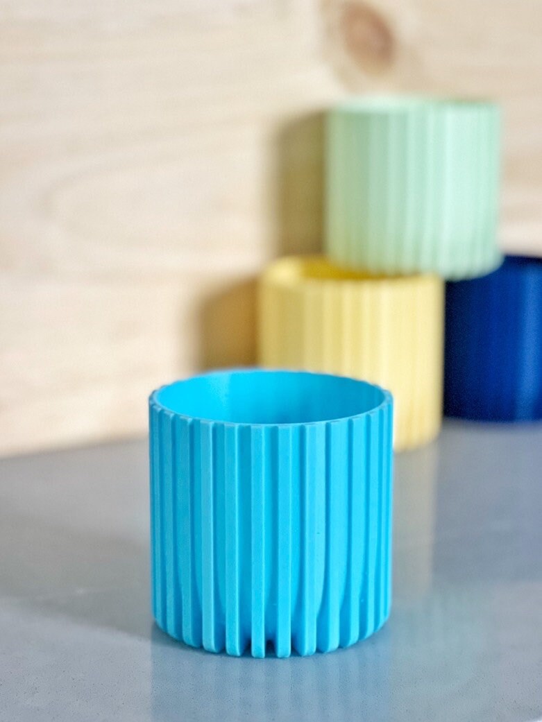Light blue Modern Fluted Planter in front, with yellow, mint green and dark blue planters behind it