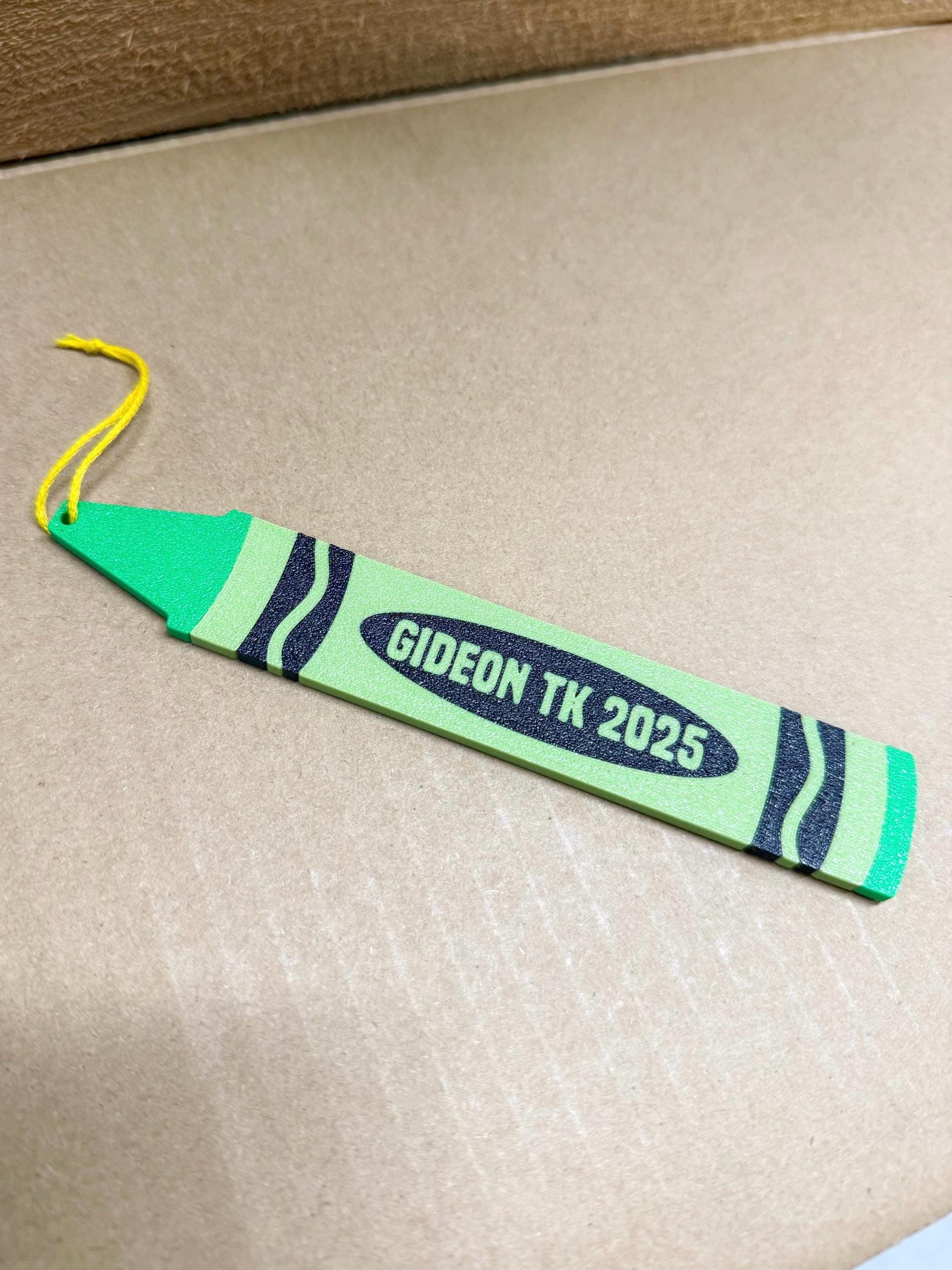 Green personalized crayon ornament reading Gideon TK 2025 on a cardboard box