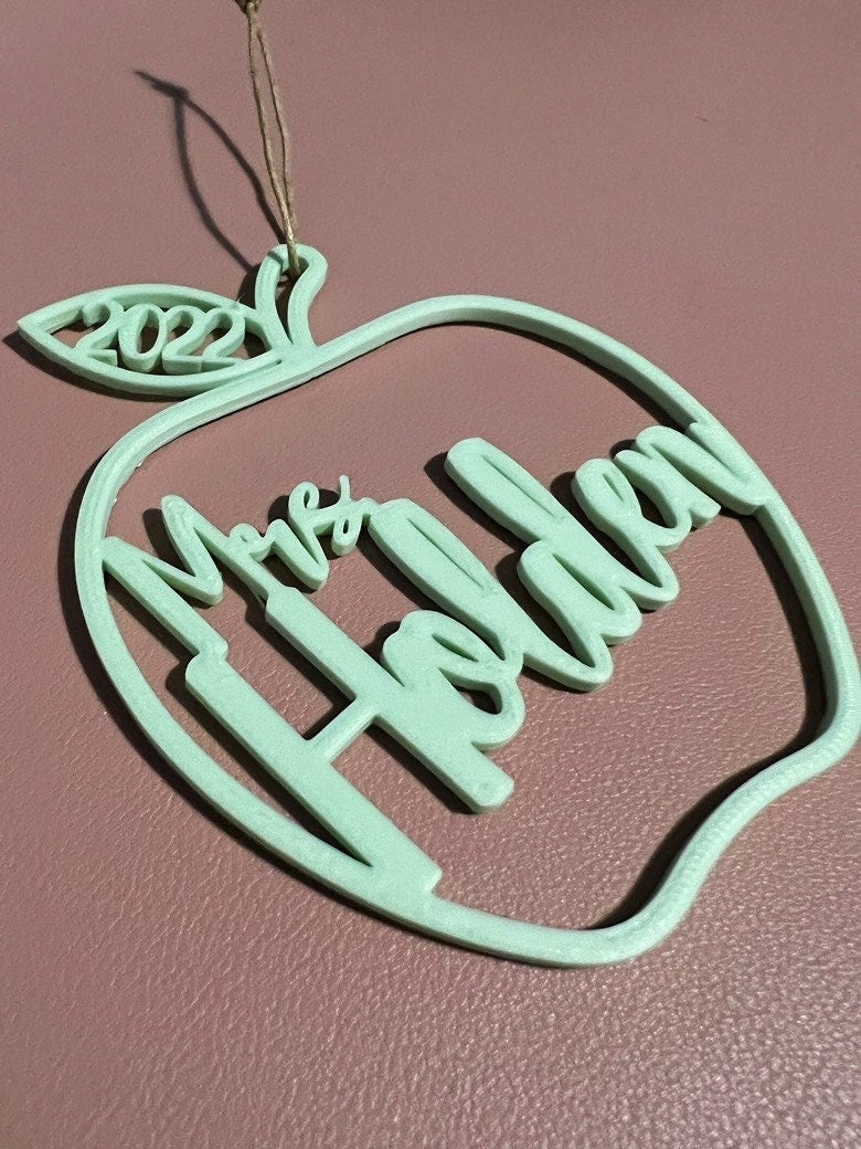 Close-up of a 3D printed mint green apple ornament reading Mrs Holden with 2022 in the leaf