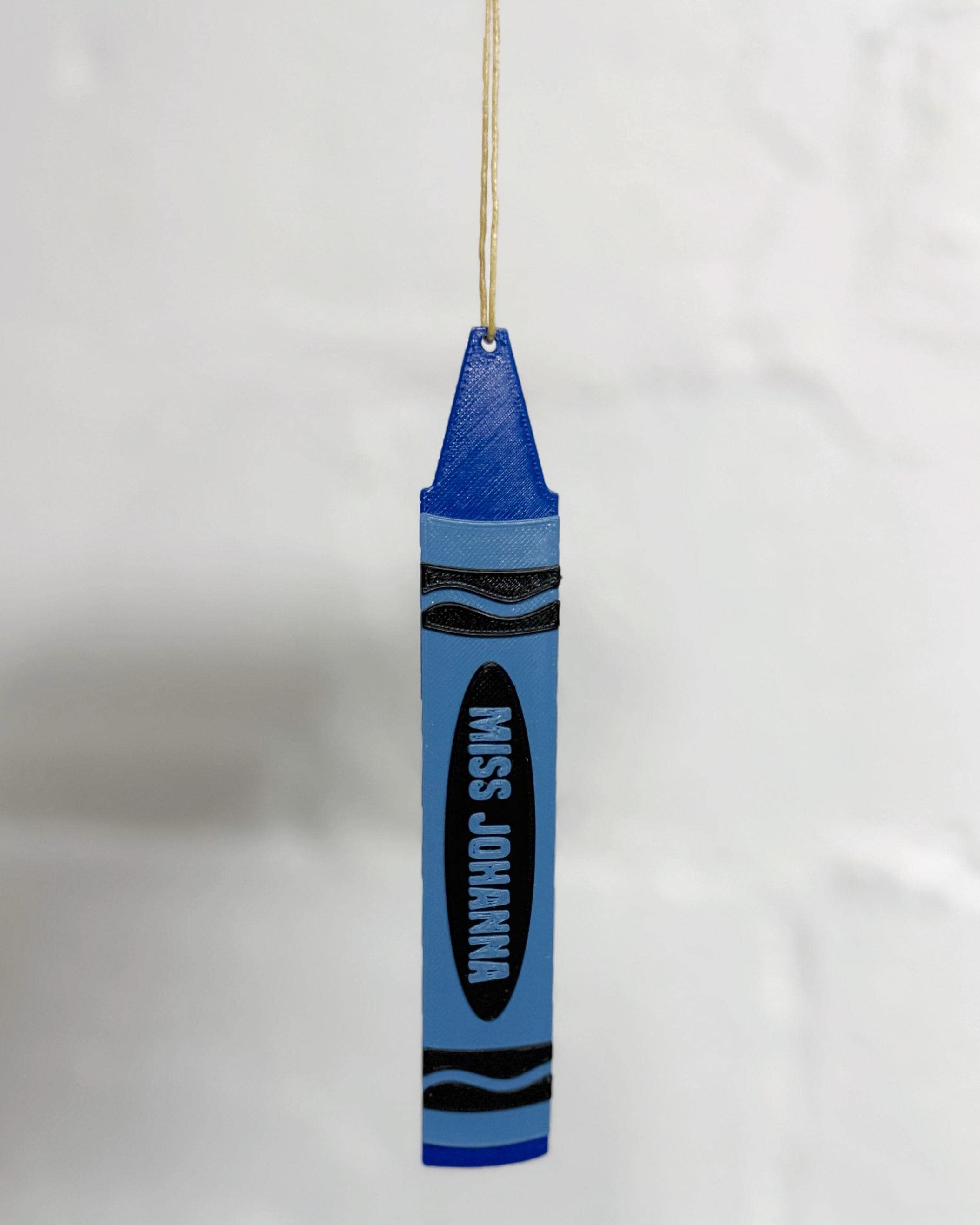 Blue personalized 3D printed crayon ornament reading Miss Johanna hanging from a string