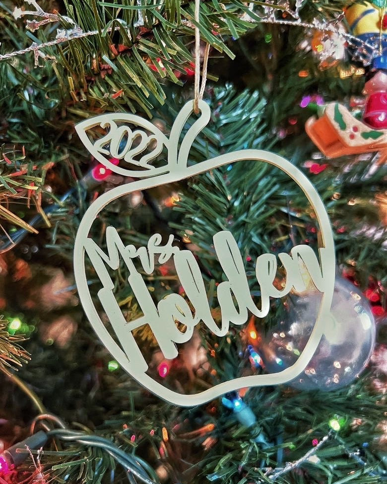Personalized mint green 3D printed apple ornament reading Mrs Holden 2022 hanging on a lit Christmas tree