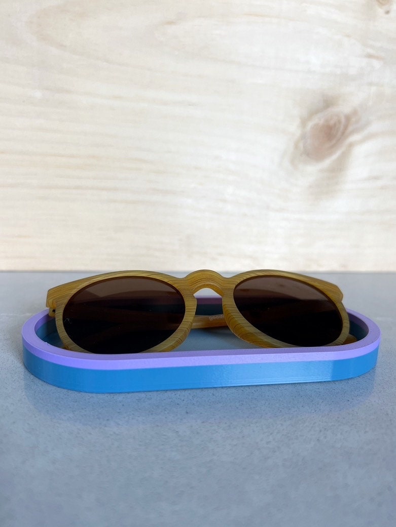 Two-tone purple and blue oval tray holding a pair of sunglasses