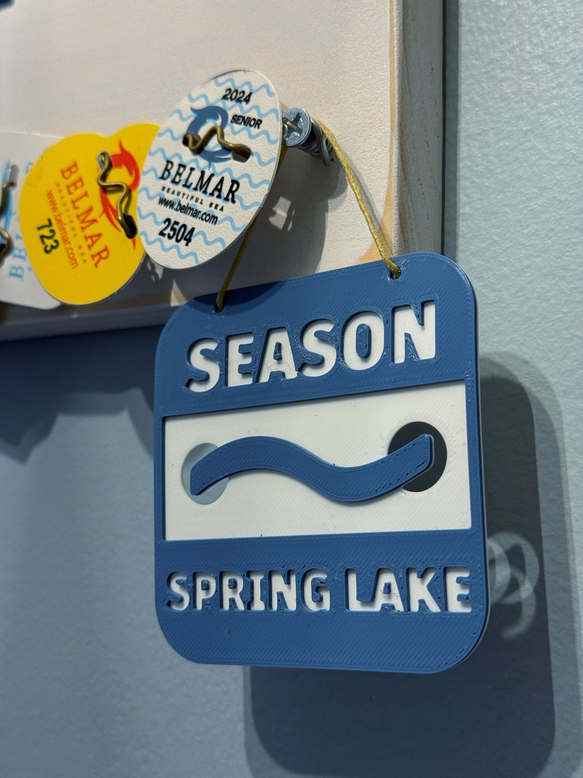 Spring Lake 3D printed beach badge ornament hanging on a wall next to real Belmar beach badges