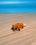Orange 3D printed Mini Flexi Fox fidget toy on a wood desk