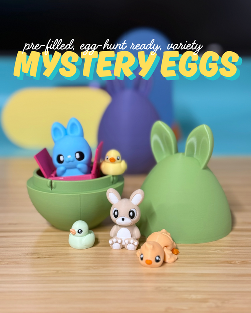 3D printed bunny ear mystery eggs in blue and green, opened to show small 3D printed toys inside: a bunny, chicks, and a duck