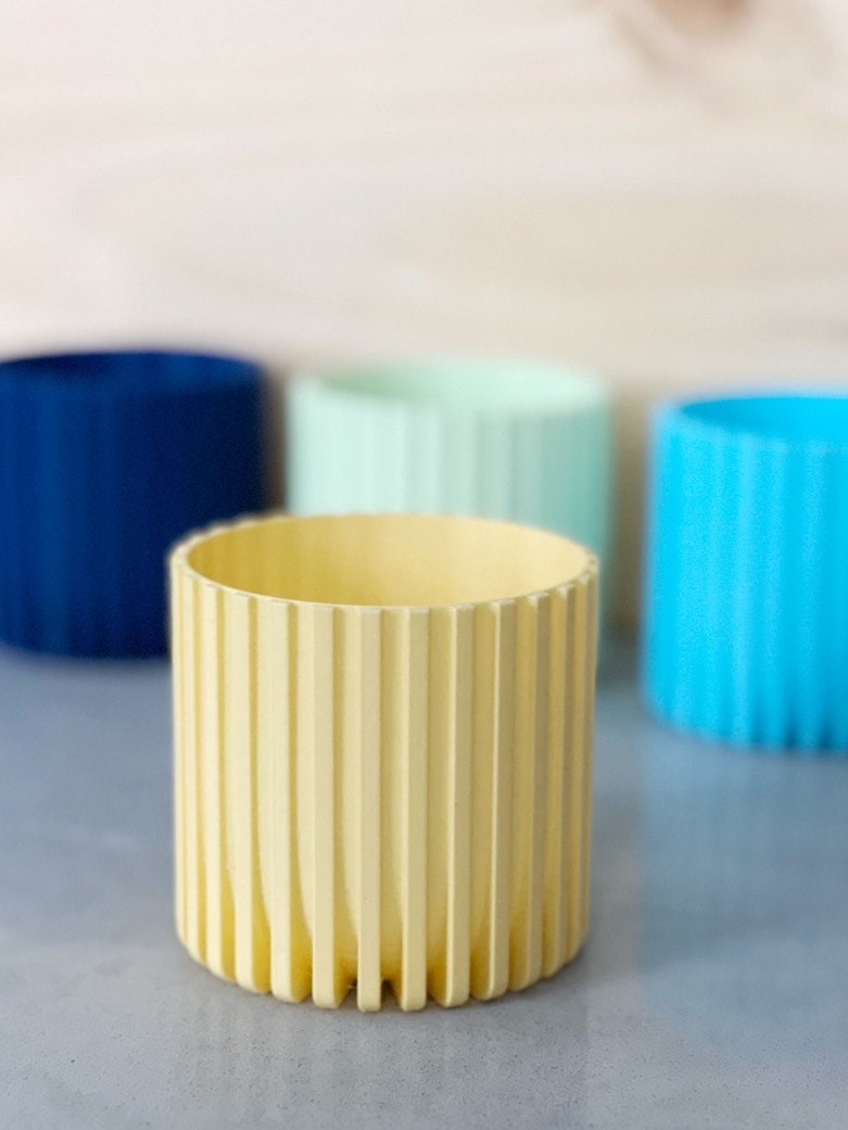 Yellow Modern Fluted Planter with mint green, dark blue and light blue planters behind it