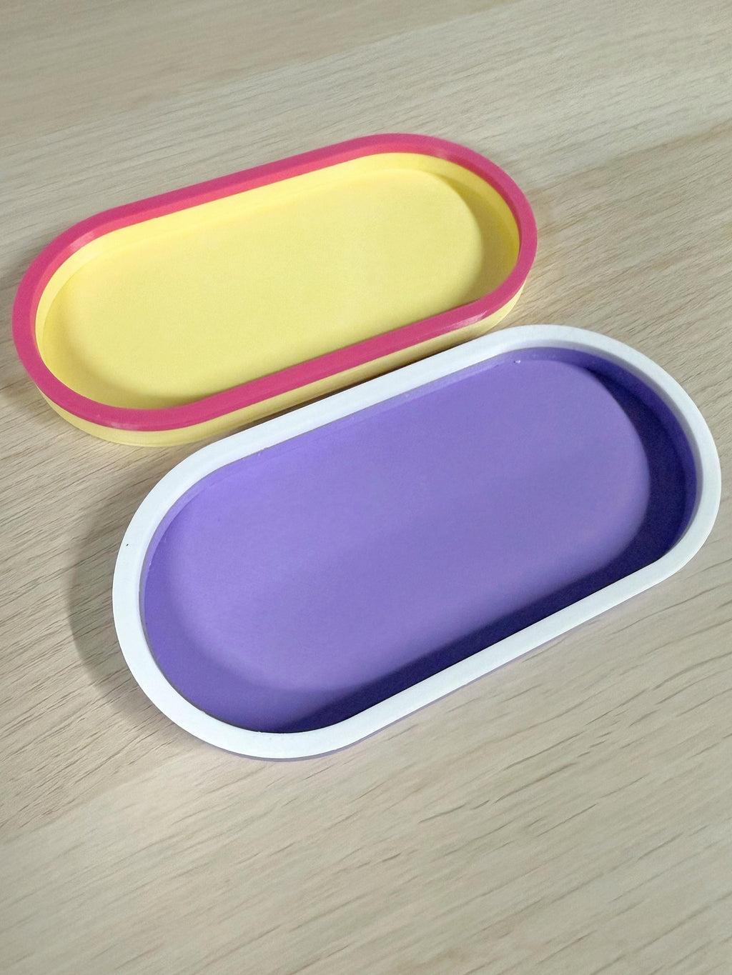 Yellow and magenta and purple and white 3D printed oval trays at an angle